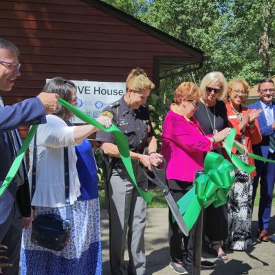 Partners involved with THRIVE House line up and cut a green ribbon in front of the home.