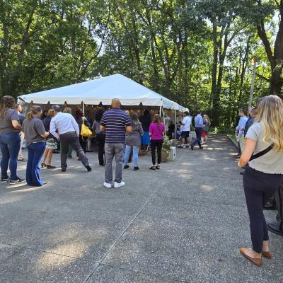 Guests gather in and around a tent to hear remarks about the THRIVE House.