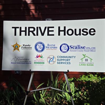 A sign for THRIVE House lists the community partners.