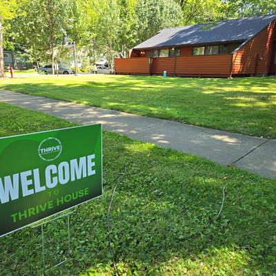 A green welcome sign in the yard welcomes visitors to THRIVE House.